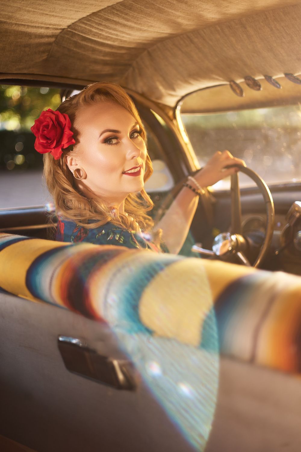 Side view through classic car window showing retro fashion and red rose hair accessory.