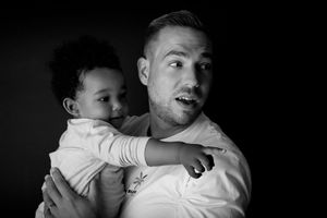 Dramatic black and white photo of adult and young child sharing playful moment together.