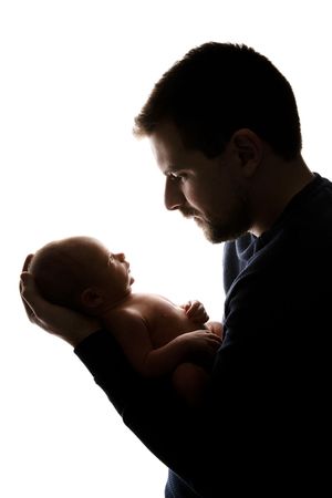 Silhouette portrait of a parent cradling and gazing lovingly at their newborn baby.