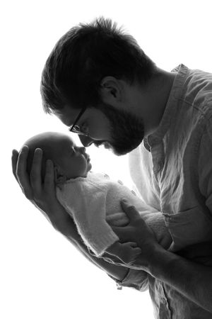 Intimate black and white portrait of a parent holding and nuzzling a newborn.