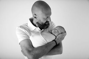 Emotional black and white photograph of a parent embracing a sleeping infant.