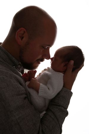 Backlit silhouette of a tender moment between a parent and infant.