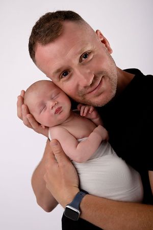 Close-up studio portrait of a parent and sleeping baby sharing an intimate moment.