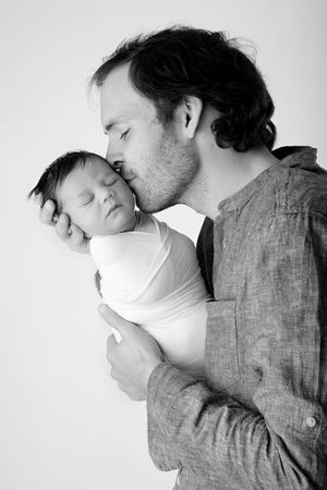 An intimate monochrome moment between a parent and infant as they share a gentle forehead touch.