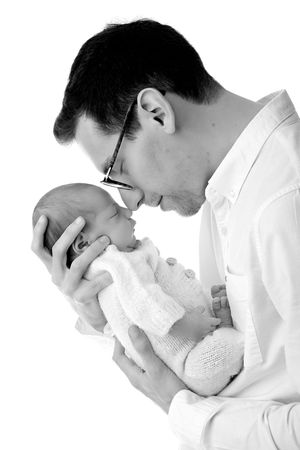 A black and white close-up of a tender moment between a person and newborn baby.