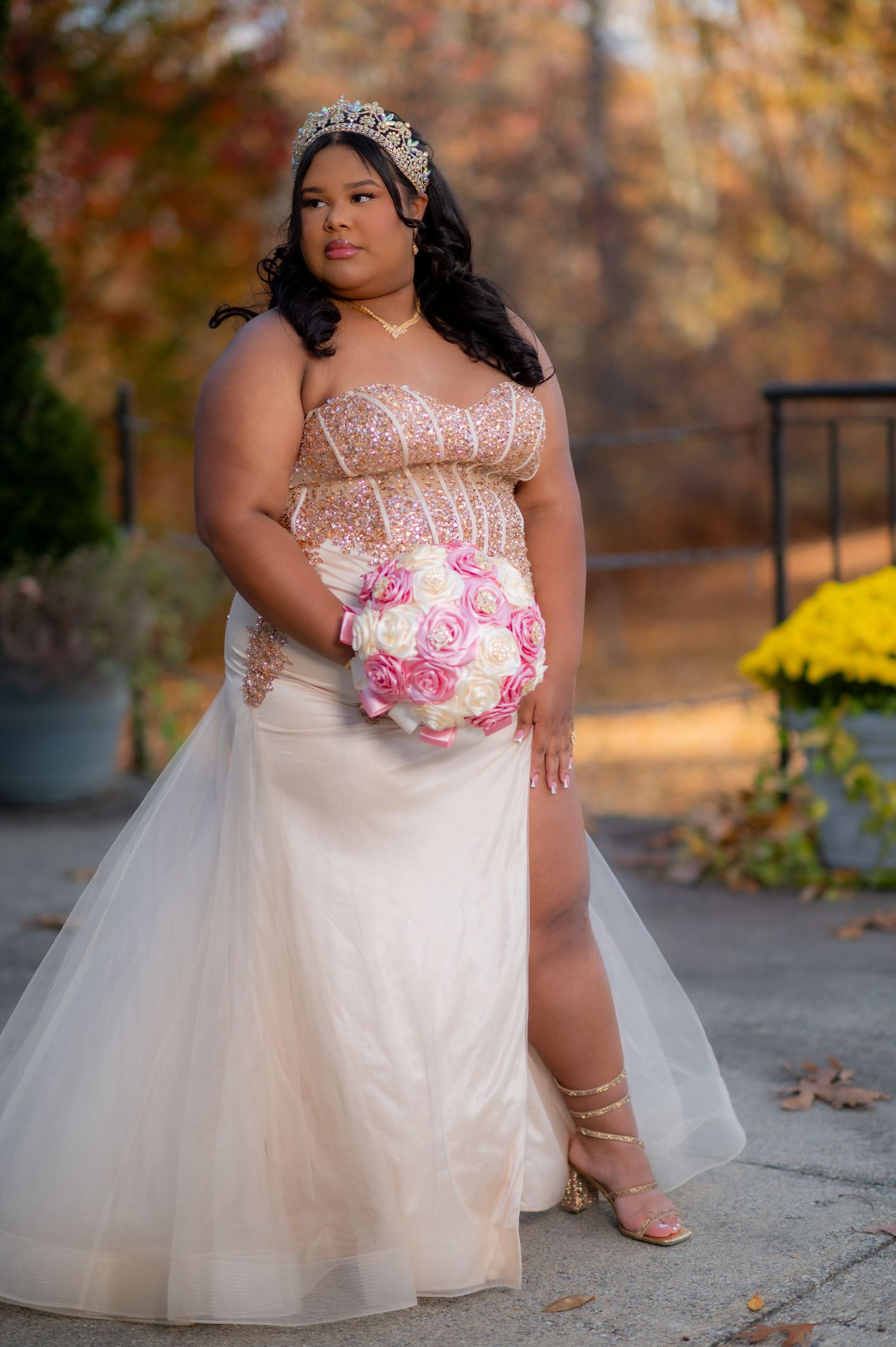Romantic bridal portrait in champagne gown with pink rose bouquet against fall foliage.