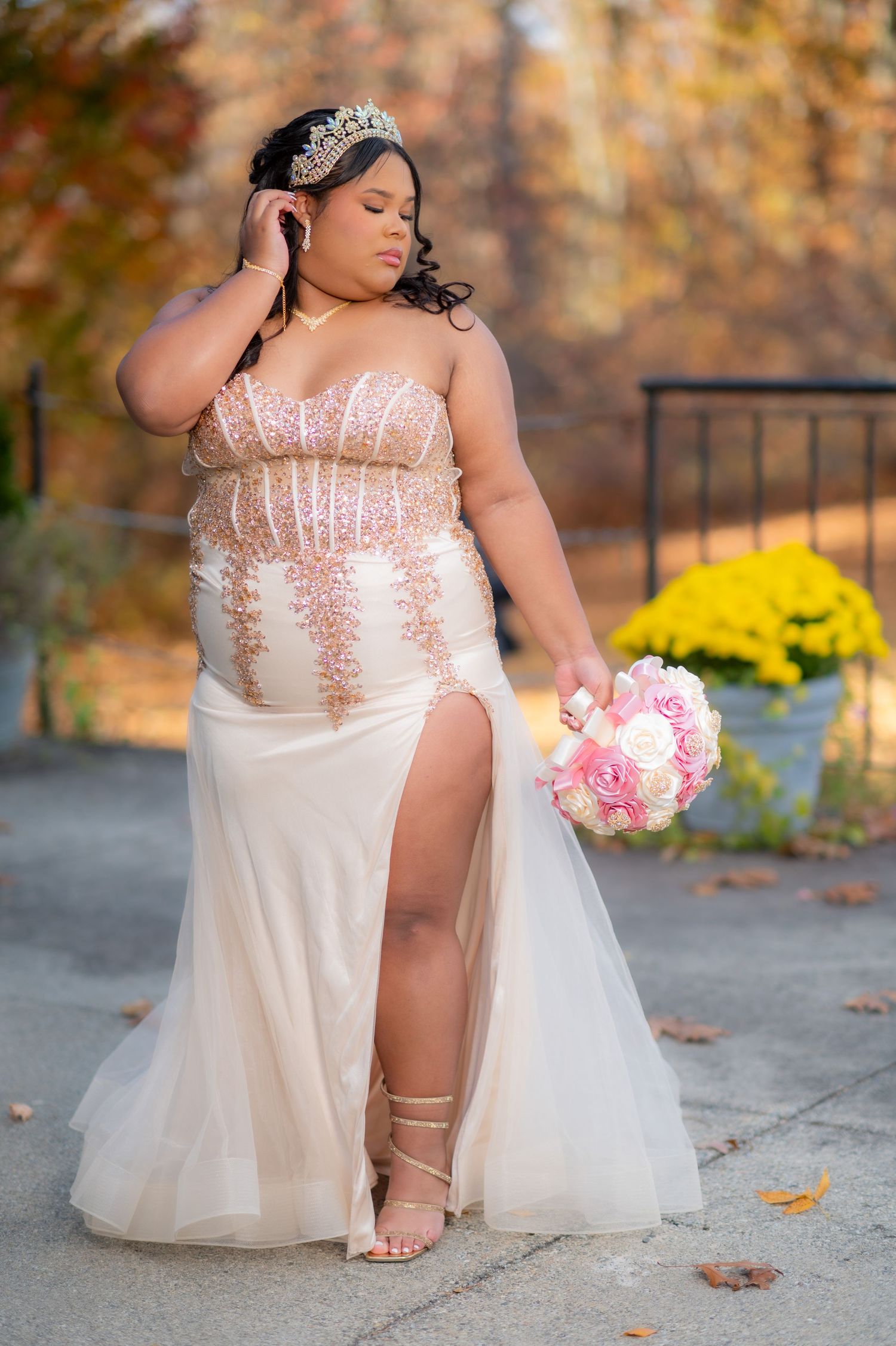 Elegant champagne wedding gown with crystal tiara and pink bouquet in autumn setting.