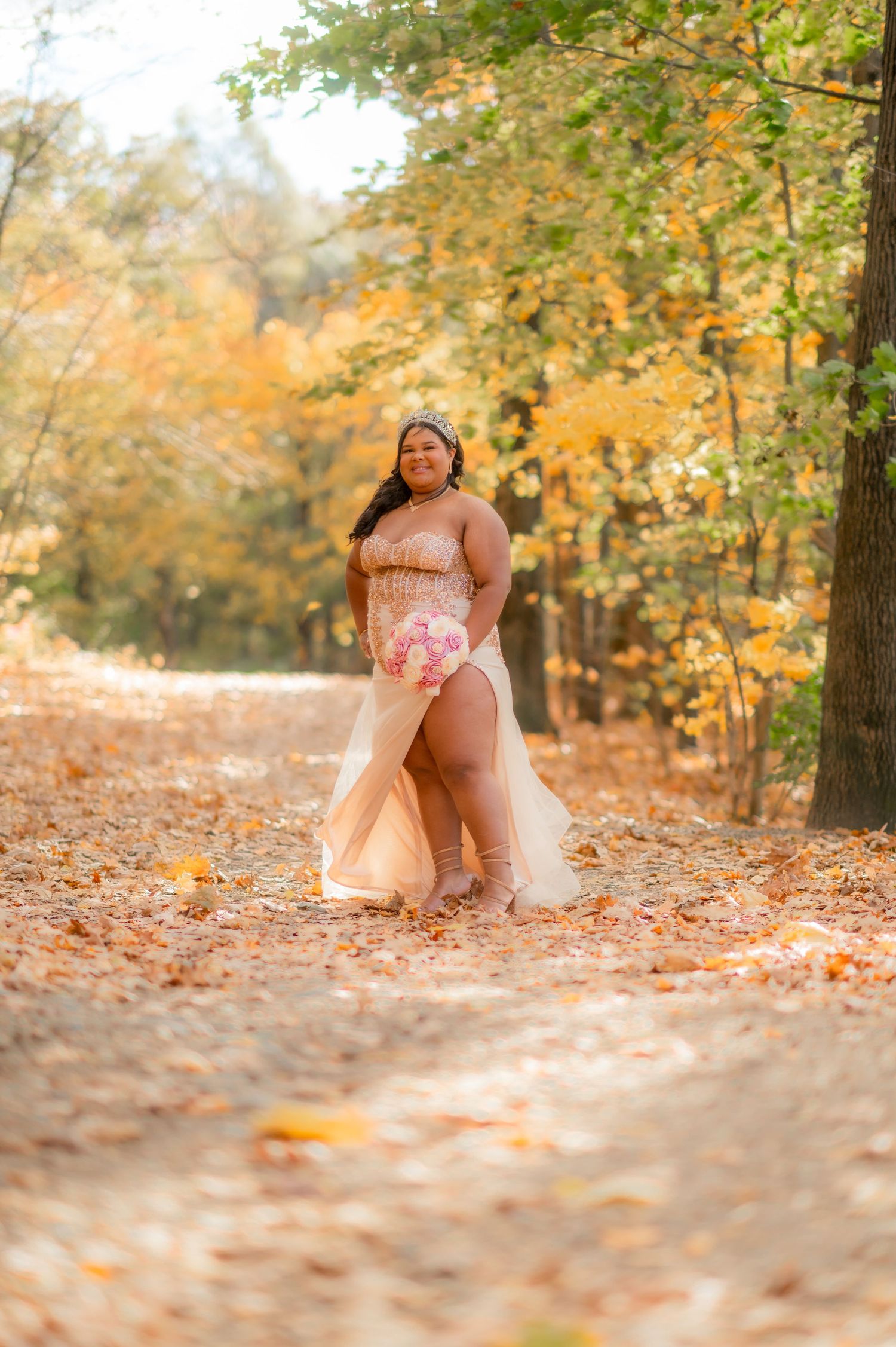 Ethereal champagne gown photographed on autumn path with golden falling leaves.