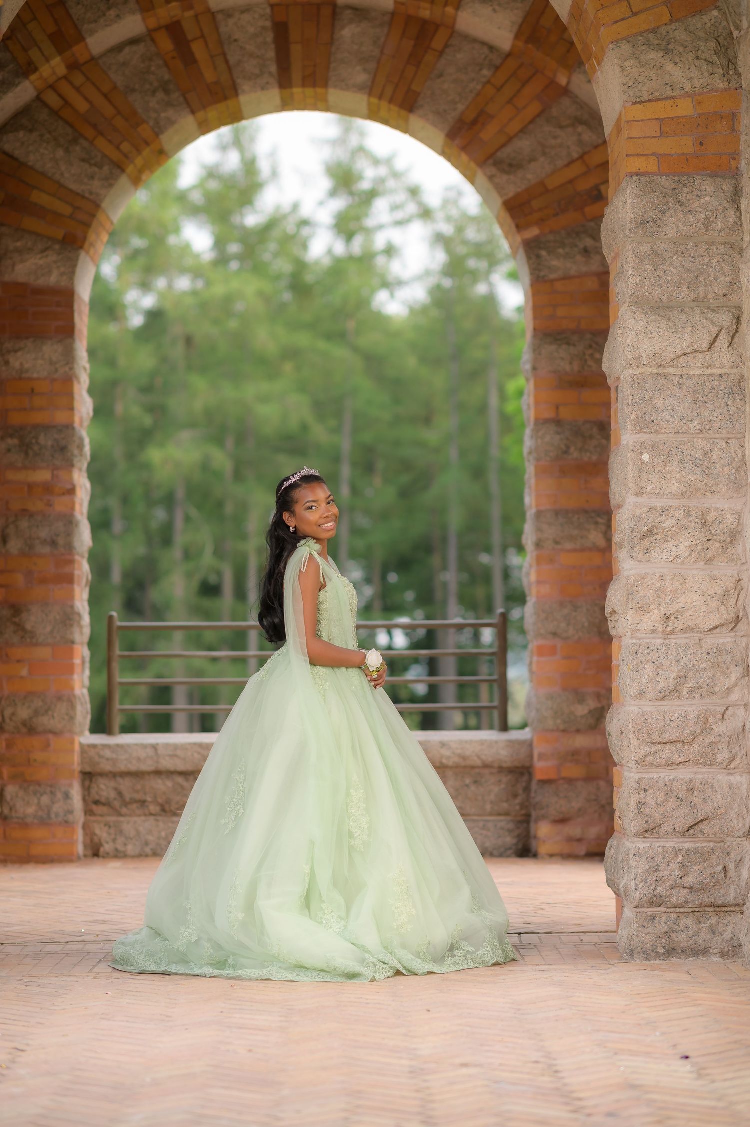 Elegant mint green wedding gown framed within stone archway architecture.