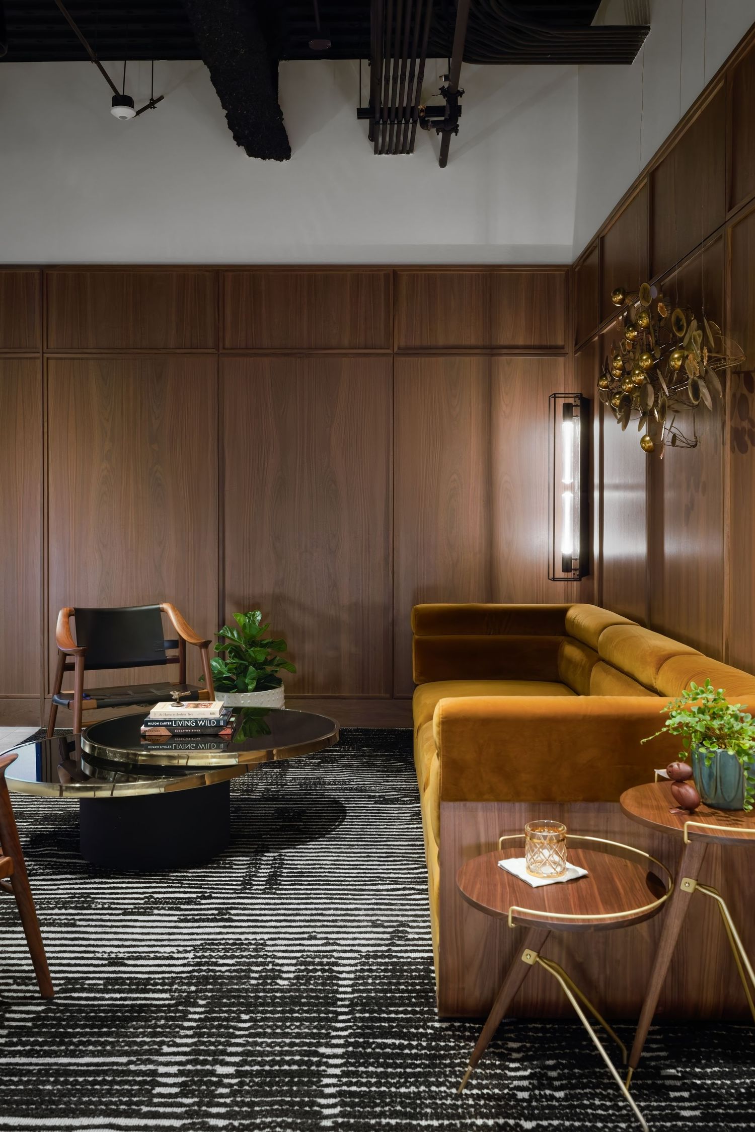 Sophisticated lounge with walnut wood-paneled walls, mustard velvet sofa, leather chair, and brass coffee table.