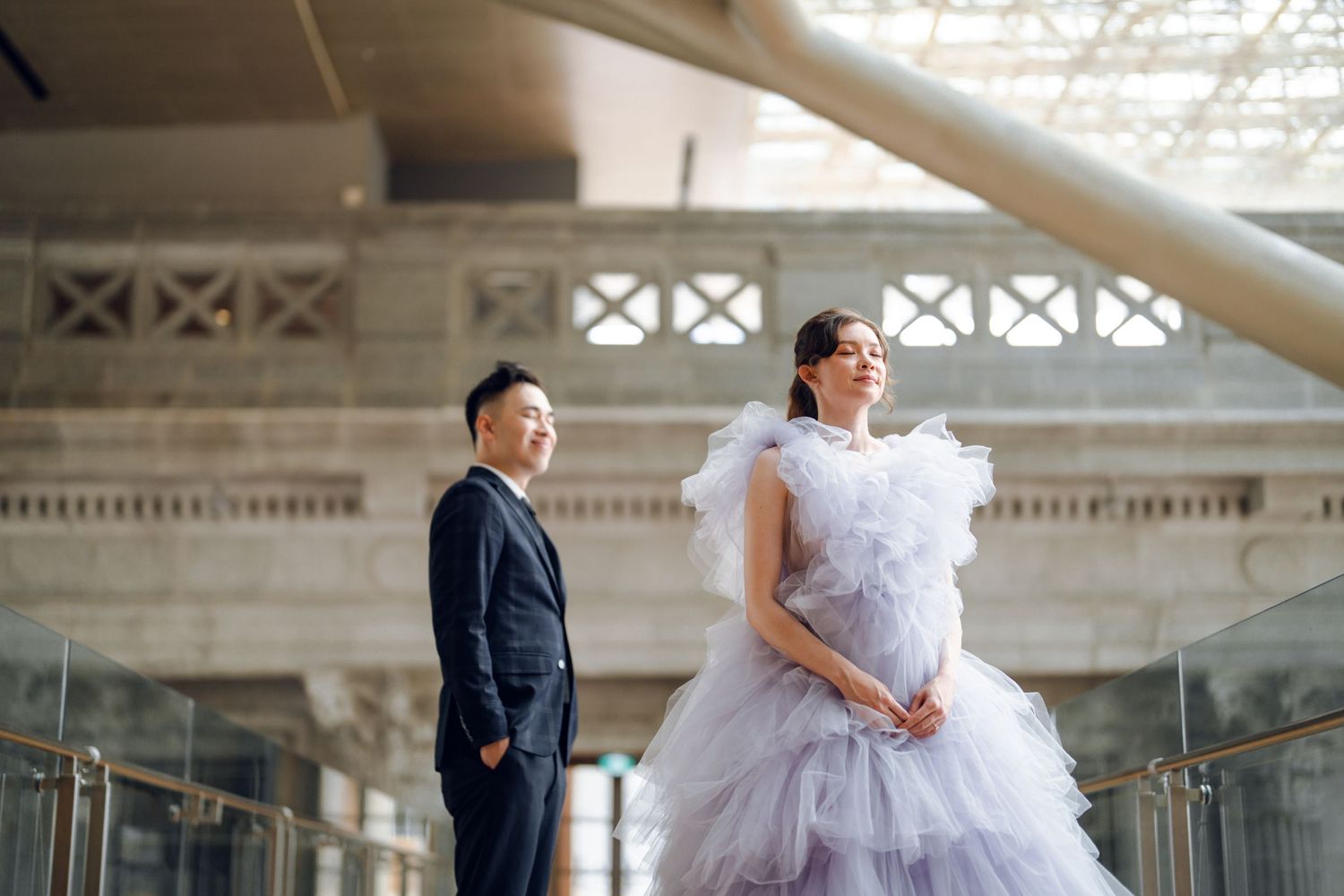 A couple poses in a bright indoor gallery space with ornate architectural details.