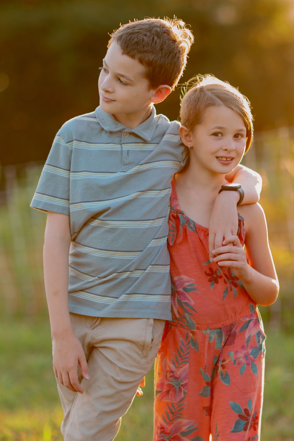 Two young people in casual attire embrace in warm sunset lighting.