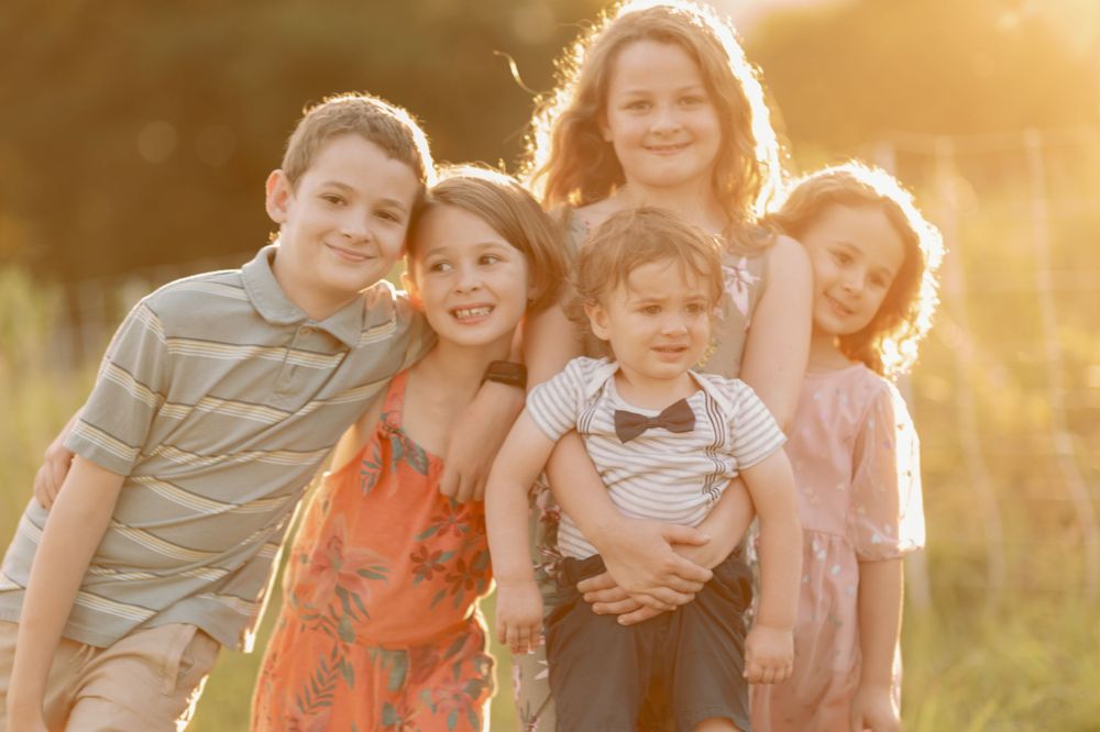 Five people huddle close together with sunlit golden hour glow behind them.