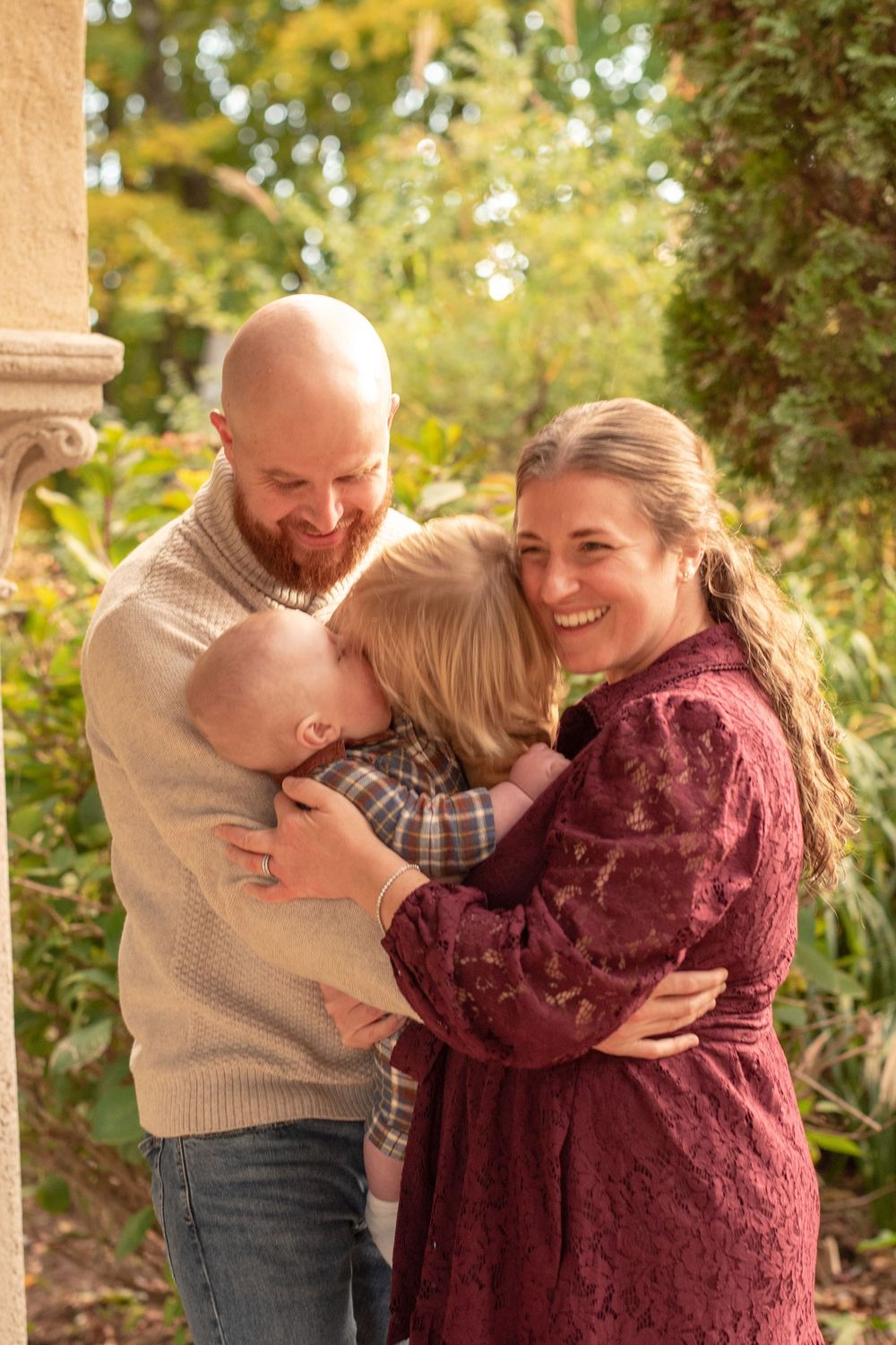A couple shares joyful laughter and embraces in a warm autumn setting with golden foliage in the background.