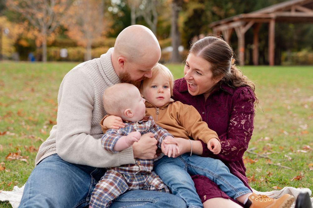 Family sitting together on grass during an outdoor autumn photo session.