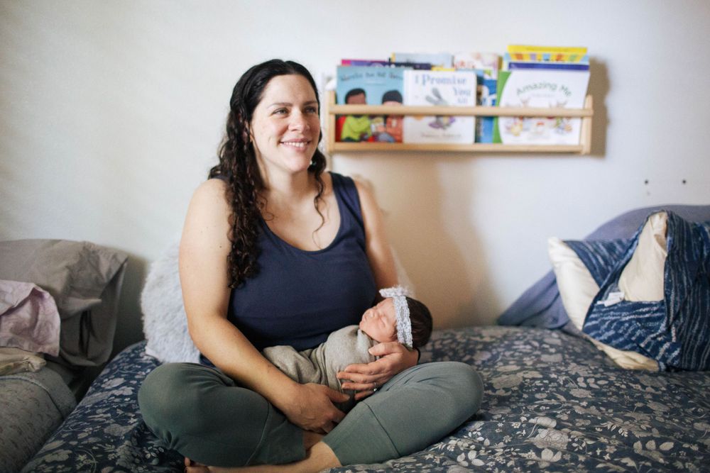 Everett WA fresh 48 photo shoot: At home with a mother holding her newborn baby in bed in Everett WA