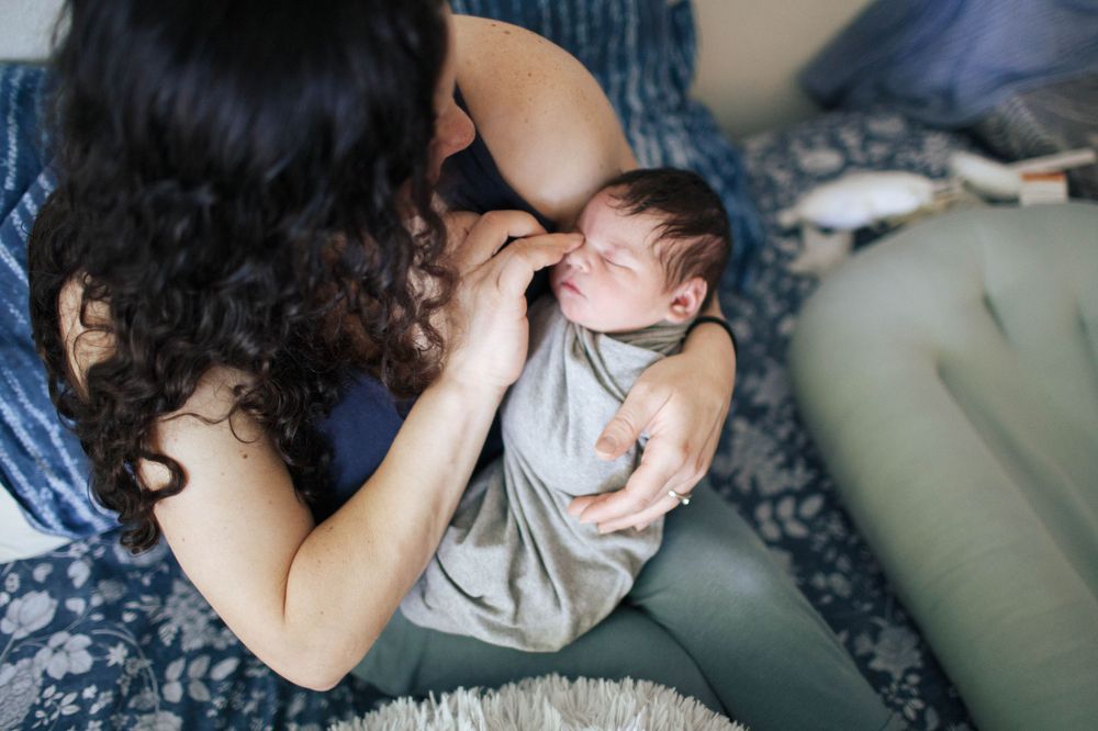 natural light fresh 48 session at home with a mother holding her newborn baby in bed in Everett WA