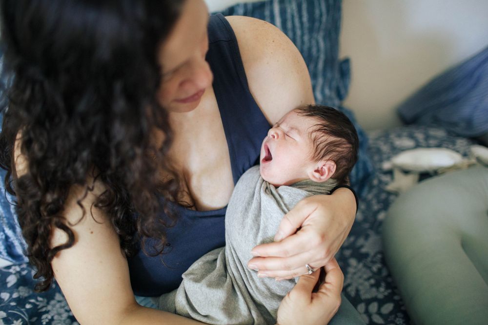natural light fresh 48 session at home with a mother holding her newborn baby in bed in Everett WA