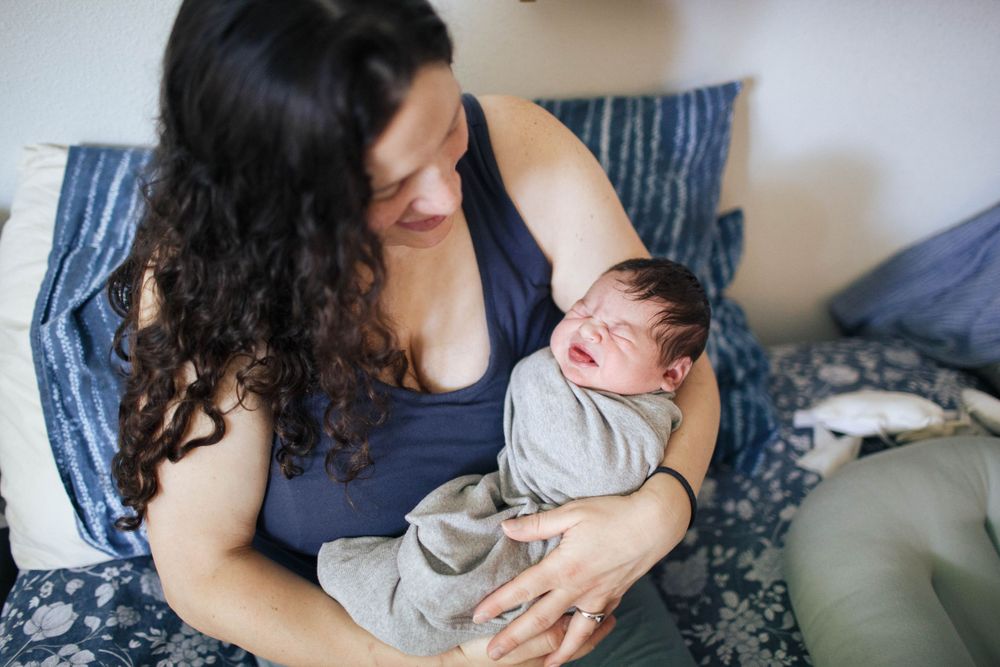 natural light fresh 48 session at home with a mother holding her newborn baby in bed in Everett WA