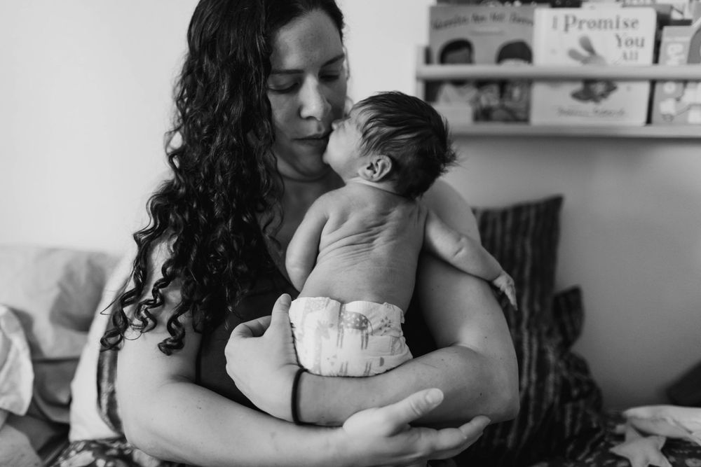 Everett WA fresh 48 photo shoot: At home with a mother holding her newborn baby in bed in Everett WA