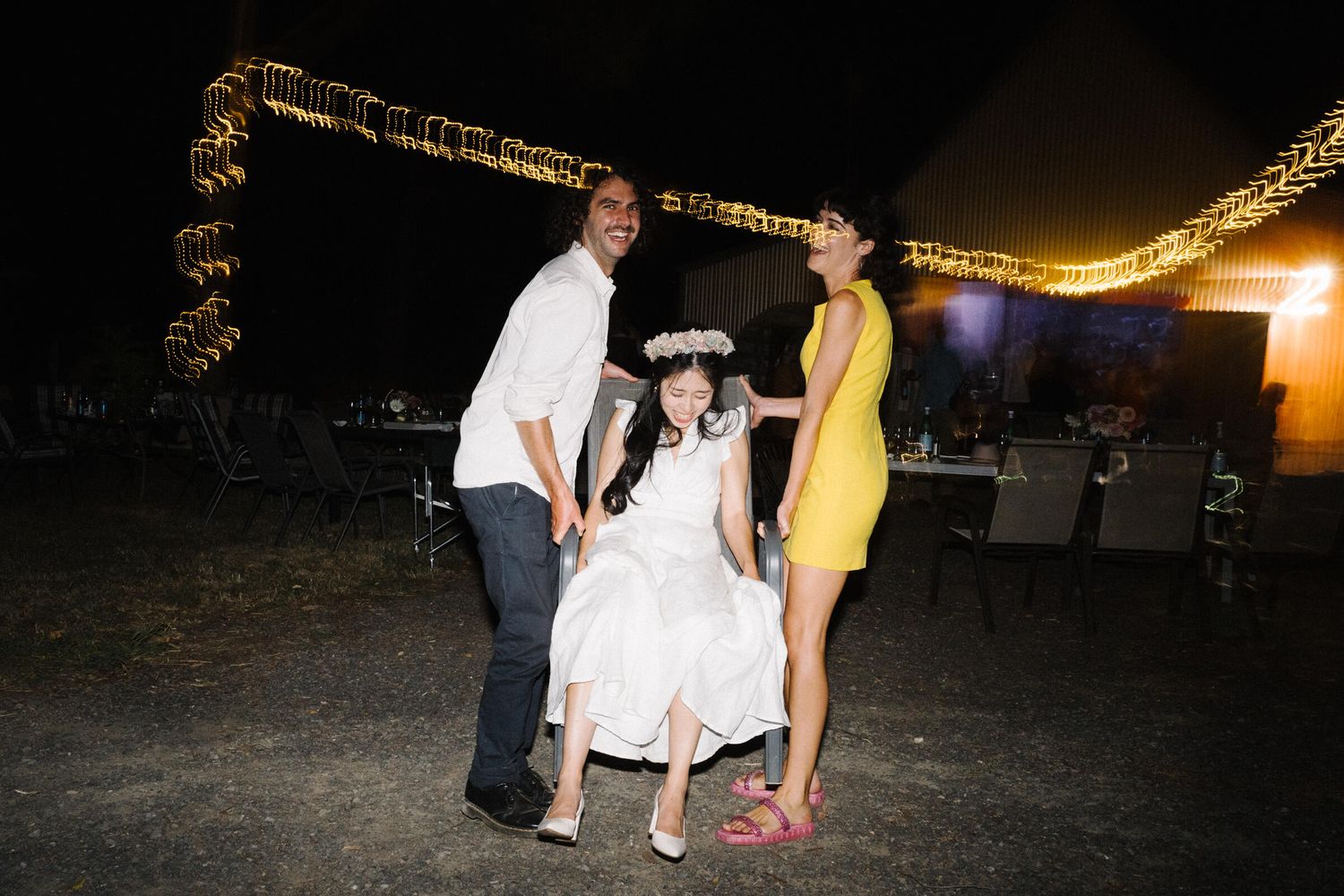 Wedding reception at Bride’s Auntie’s Barn, Woodend, Victoria, with Ellen’s friends lifting her in a chair for fun.