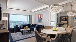 Modern penthouse living space featuring crystal chandelier, blue sectional, and panoramic city views.