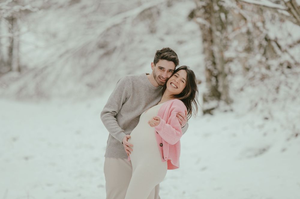 Romantic winter photo shoot of a couple in matching neutral tones against a snowy backdrop.