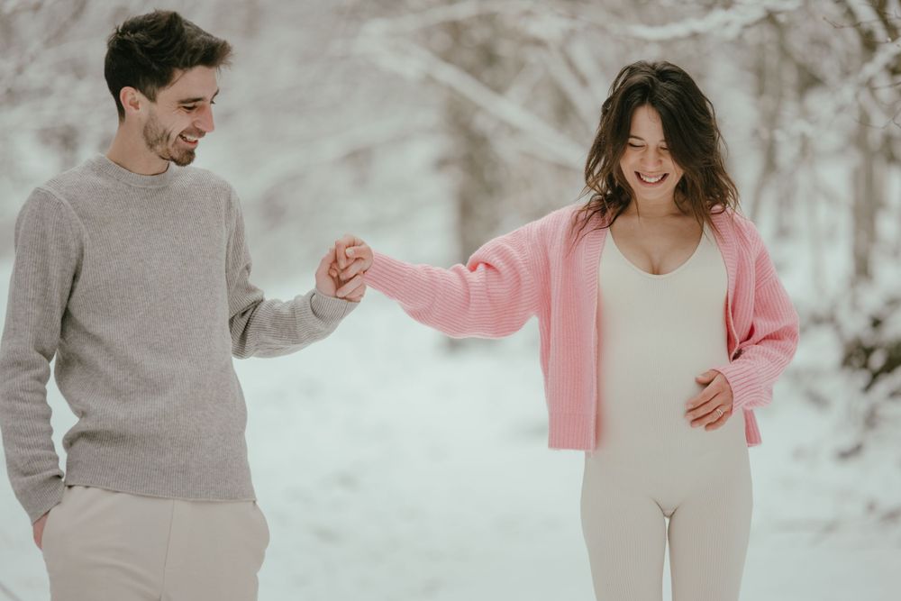 Playful winter moment captured between a couple wearing coordinated casual outfits in the snow.