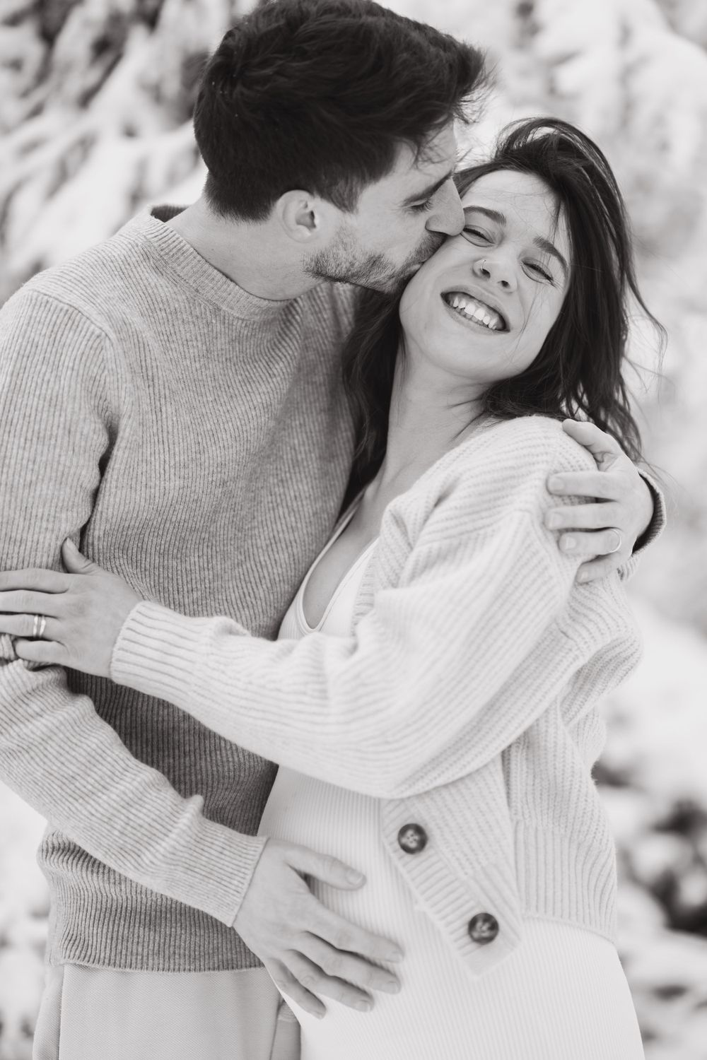 A couple shares a tender moment together against a snowy winter backdrop.