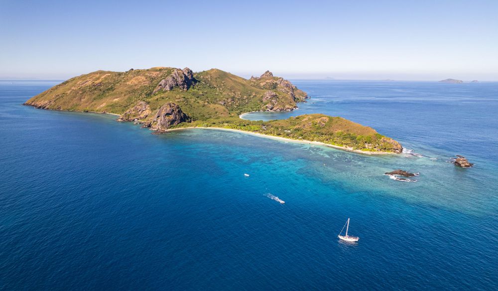 Aerial view of tropical island with pristine beach and surrounding turquoise waters.