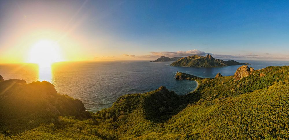 Dramatic sunset view over mountainous islands and bays from an elevated coastal viewpoint.