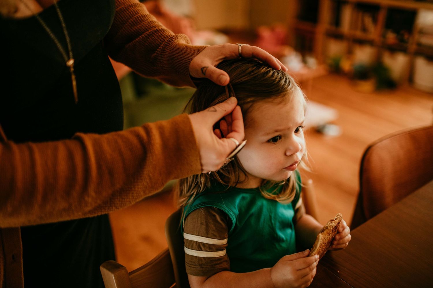 mom puts clip in child's hair during snack time portland oregon family photographer kimberly marie kimble
