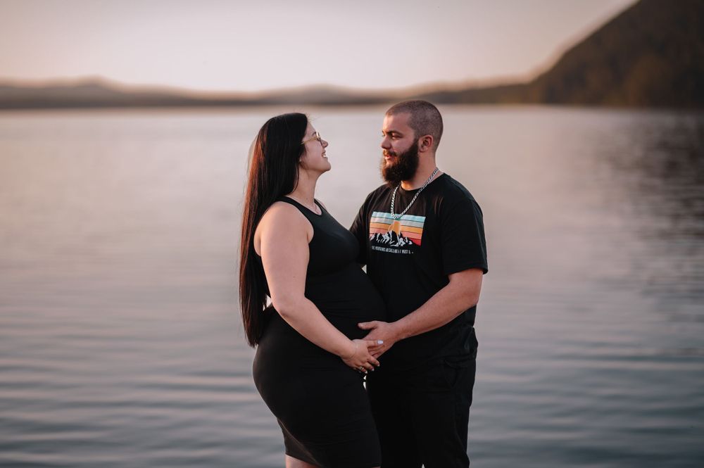 Couple shares intimate moment at lakeside during sunset photoshoot.
