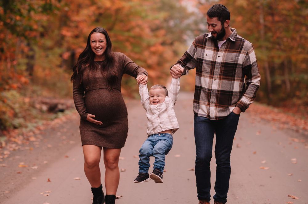 Family walking together on an autumn path surrounded by fall foliage.