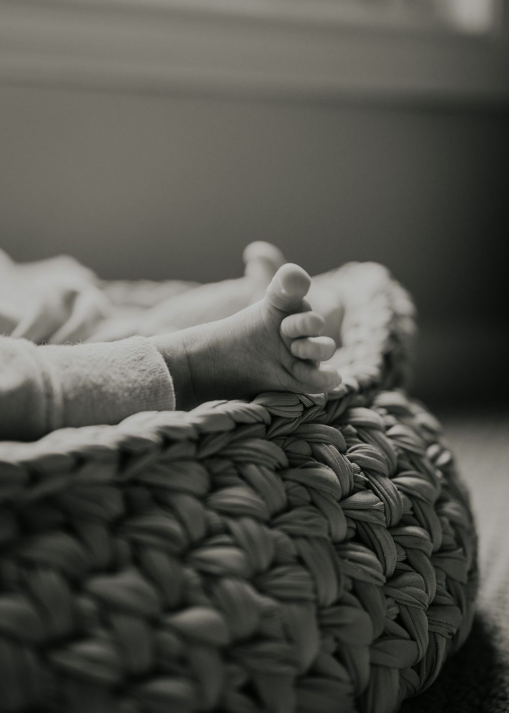 Black and white image of baby's feet resting on a textured knit blanket.