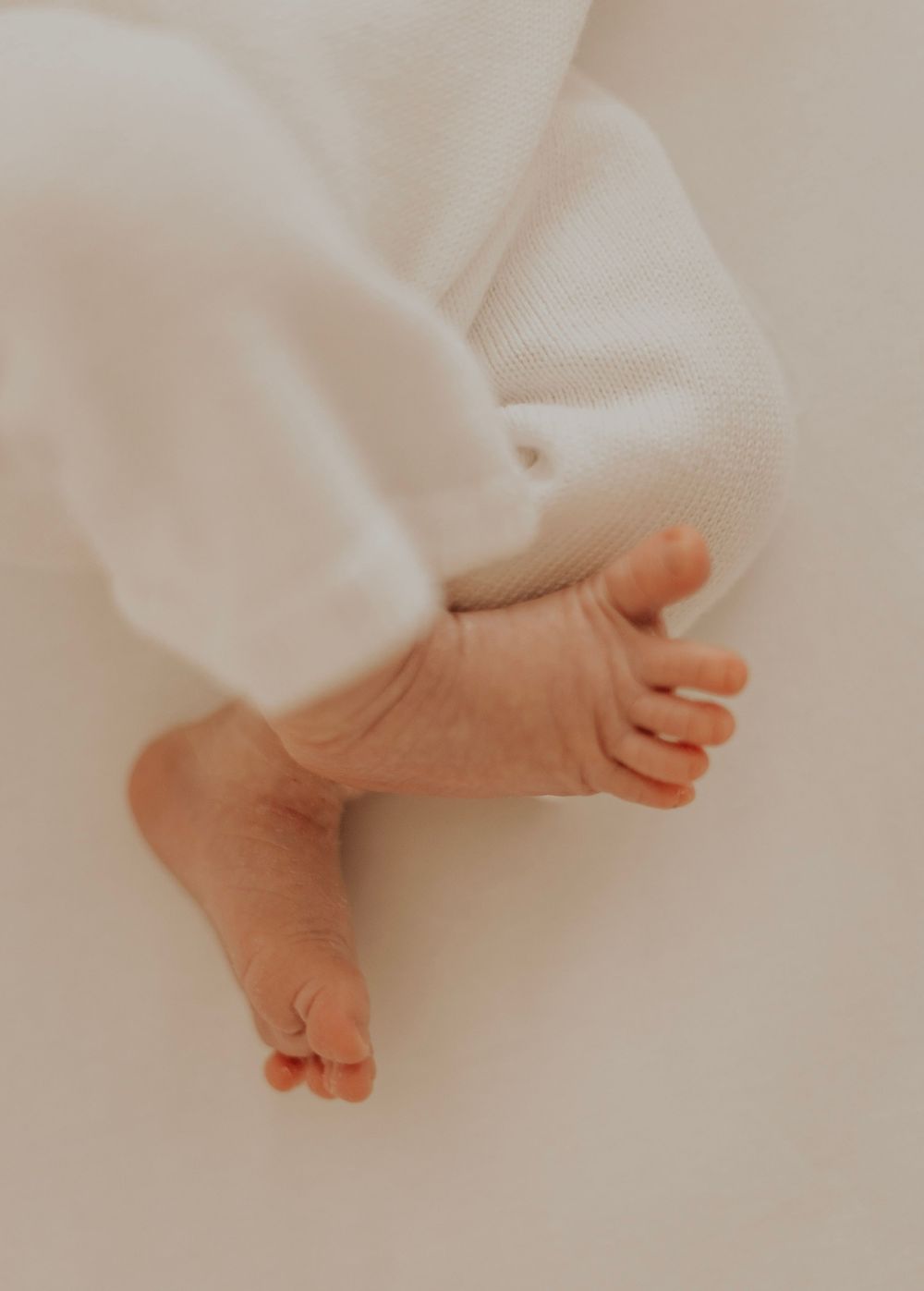 Close-up of tiny baby feet against white fabric in soft lighting.