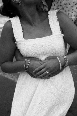 Black and white close-up of white eyelet dress with jewelry details.