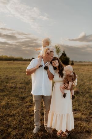 Candid family portrait shows joyful interaction in an open meadow.
