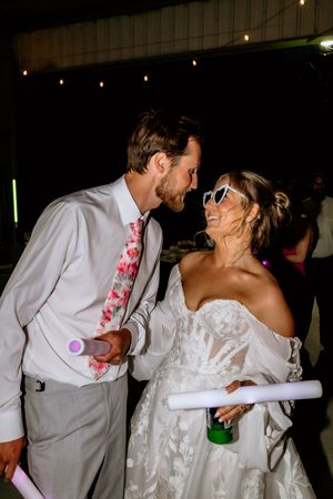 Bride and groom share a romantic moment on the dance floor, holding glow sticks at their wedding reception.