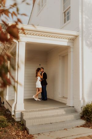 Couple sharing intimate moment in white columned entrance way.