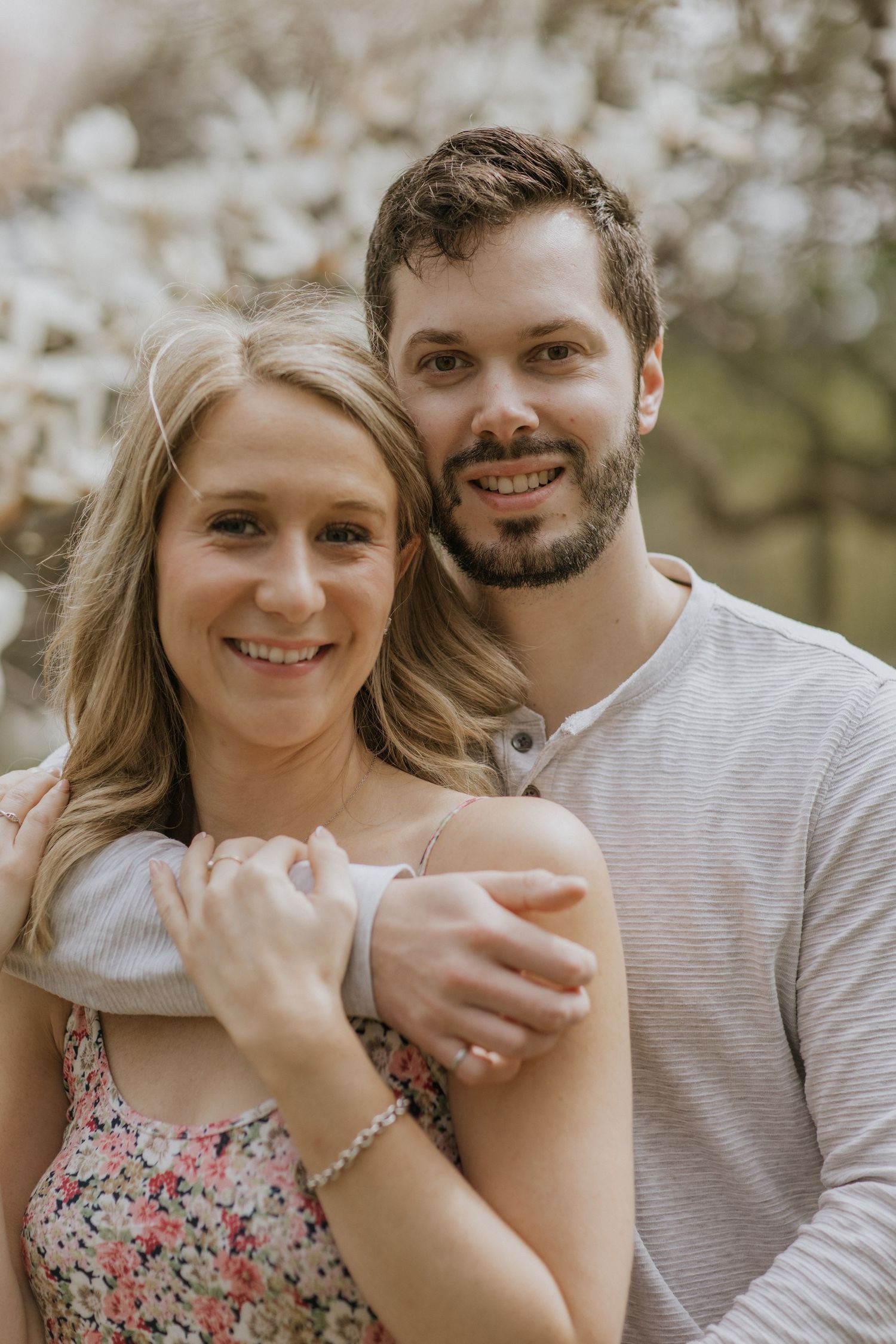 Romantic couple poses together during springtime cherry blossom photoshoot.
