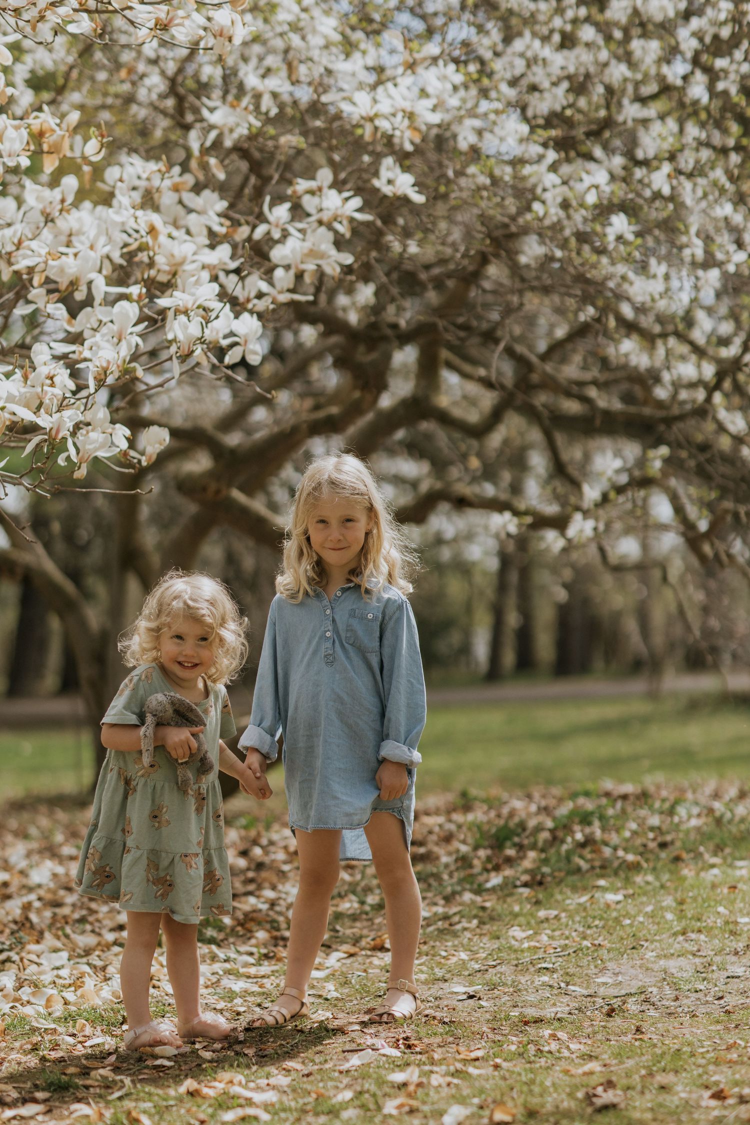Young friends walking beneath flowering cherry trees in a spring garden setting.