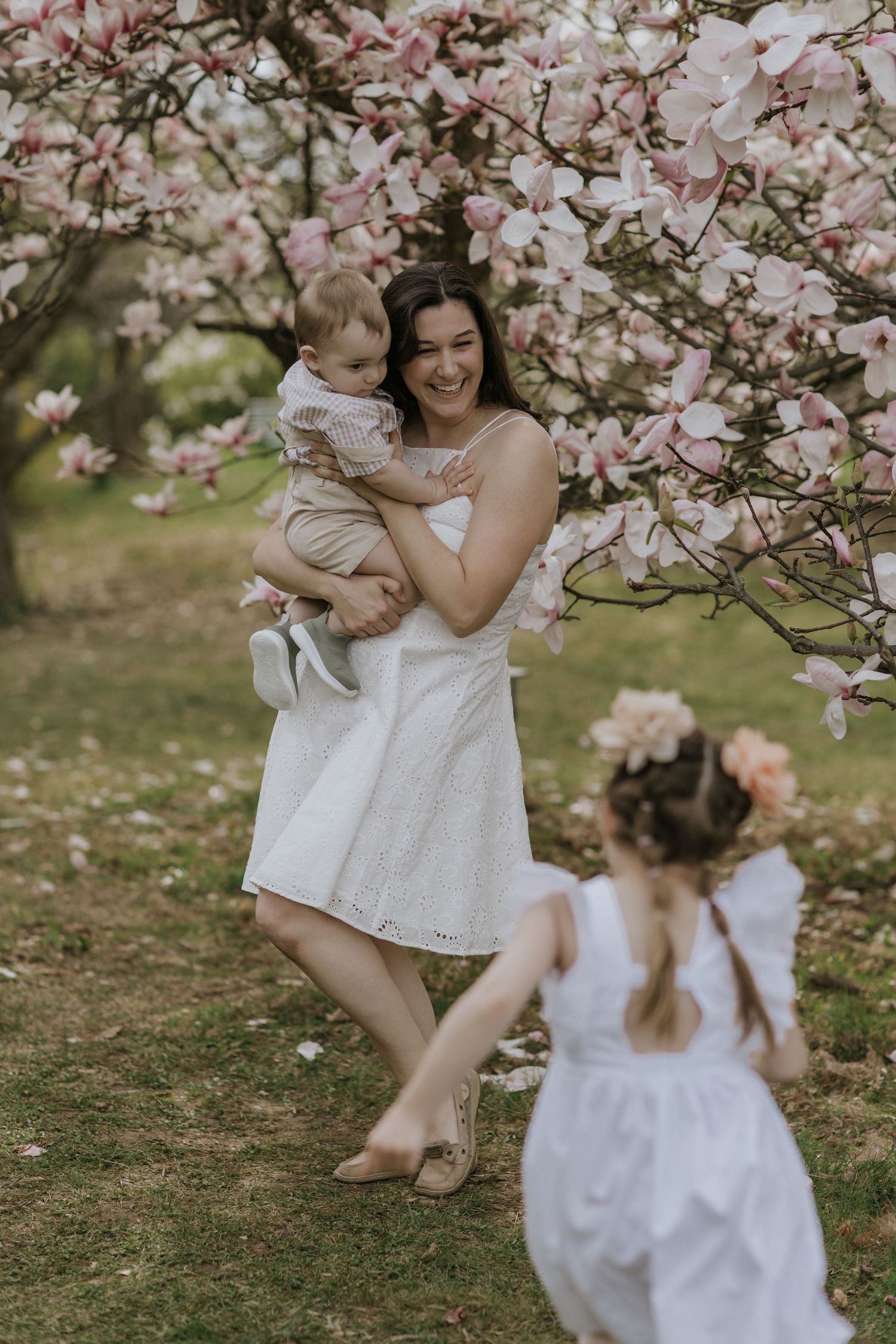 Family enjoying a tender moment together under blooming magnolia trees.