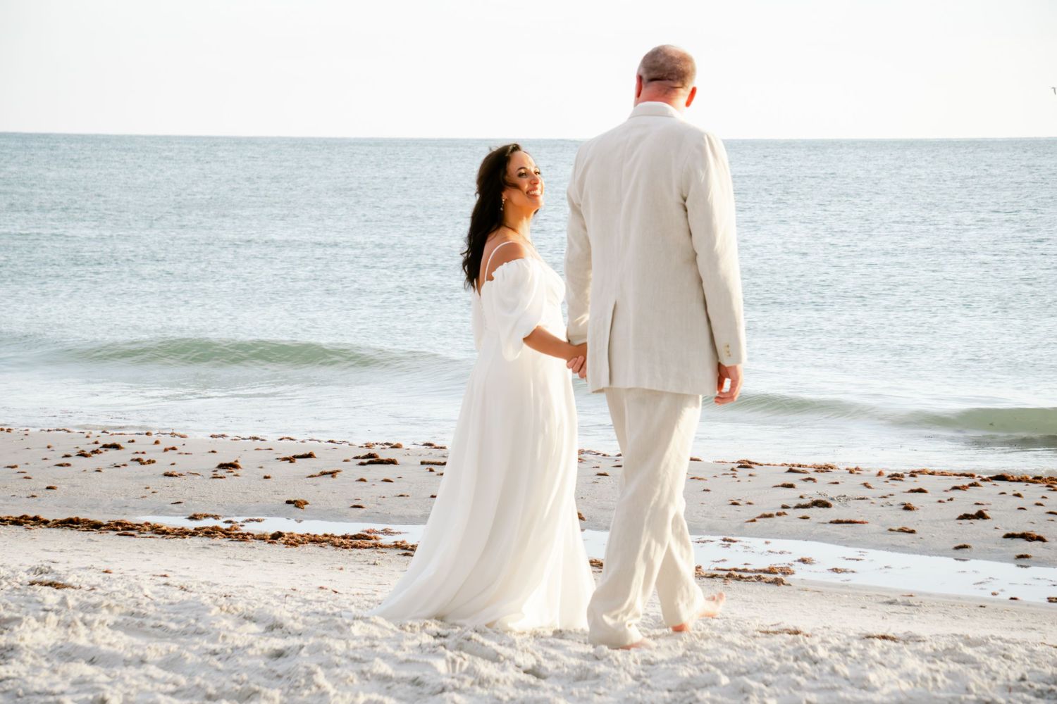Bride and groom walking hand in hand by the Treasure Island Beach shore