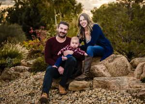 Family sitting together on large rocks in a garden setting during golden hour outdoor portrait session.