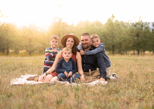 A family sitting together on a blanket in a sun-drenched meadow during golden hour.