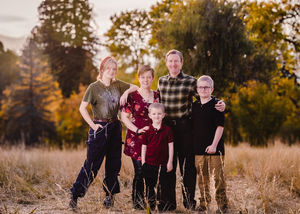 Group wearing casual clothing poses together outdoors in a field during golden autumn sunset.