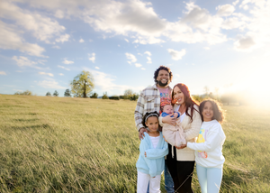 Happy group standing together in golden field at sunset in heartwarming outdoor family photograph.