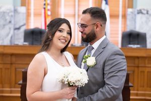 Wedding ceremony in elegant courthouse setting with white floral bouquet.