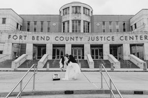 Black and white photo of newlyweds posing in front of Fort Bend County Justice Center.